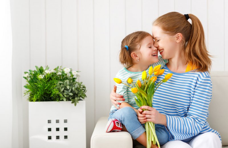 Девочка дарит цветы маме
